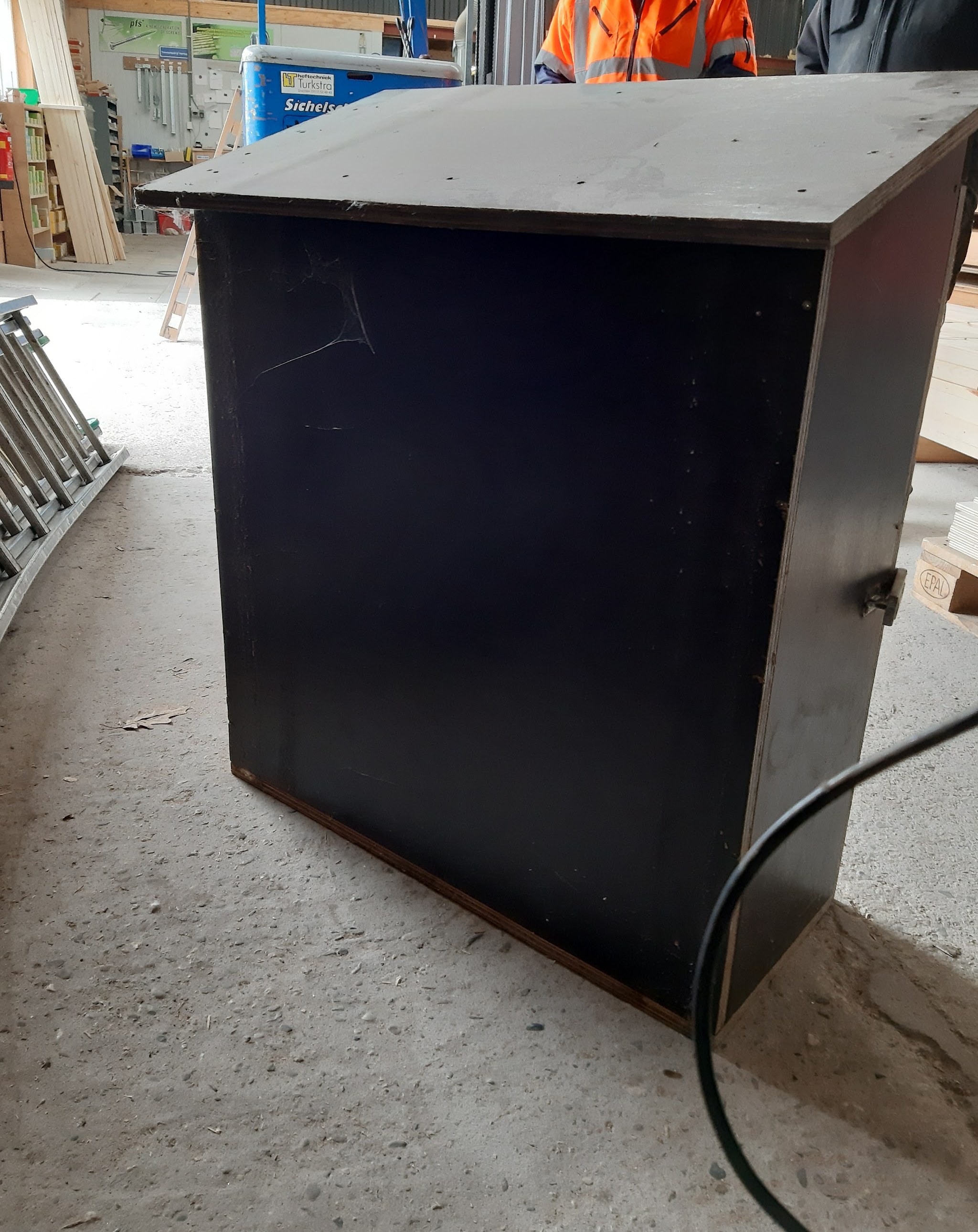 Zwarte kast met een houten rand op de betonvloer van de werkplaats